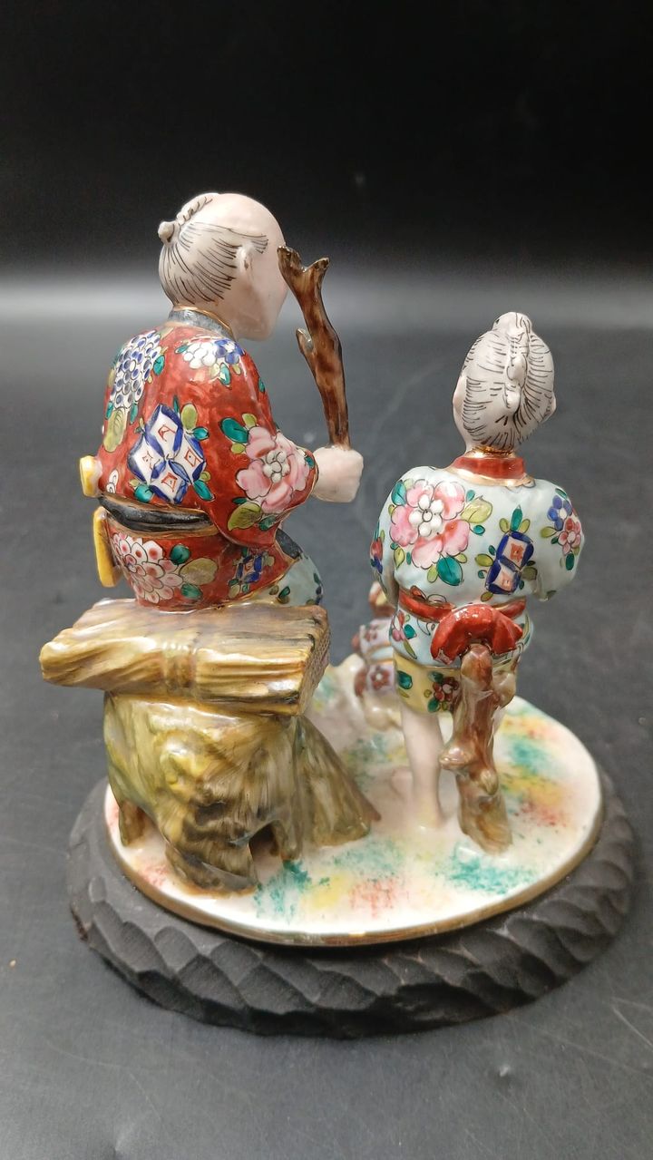 Grupo escultórico em porcelana com duas figuras asiáticas, vista lateral com os quimonos pintados