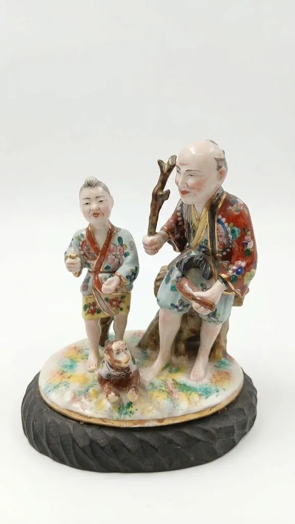Grupo escultórico em porcelana com duas figuras asiáticas, vista de três quartos